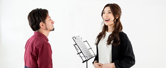 先生と向き合って歌のレッスンをする女性